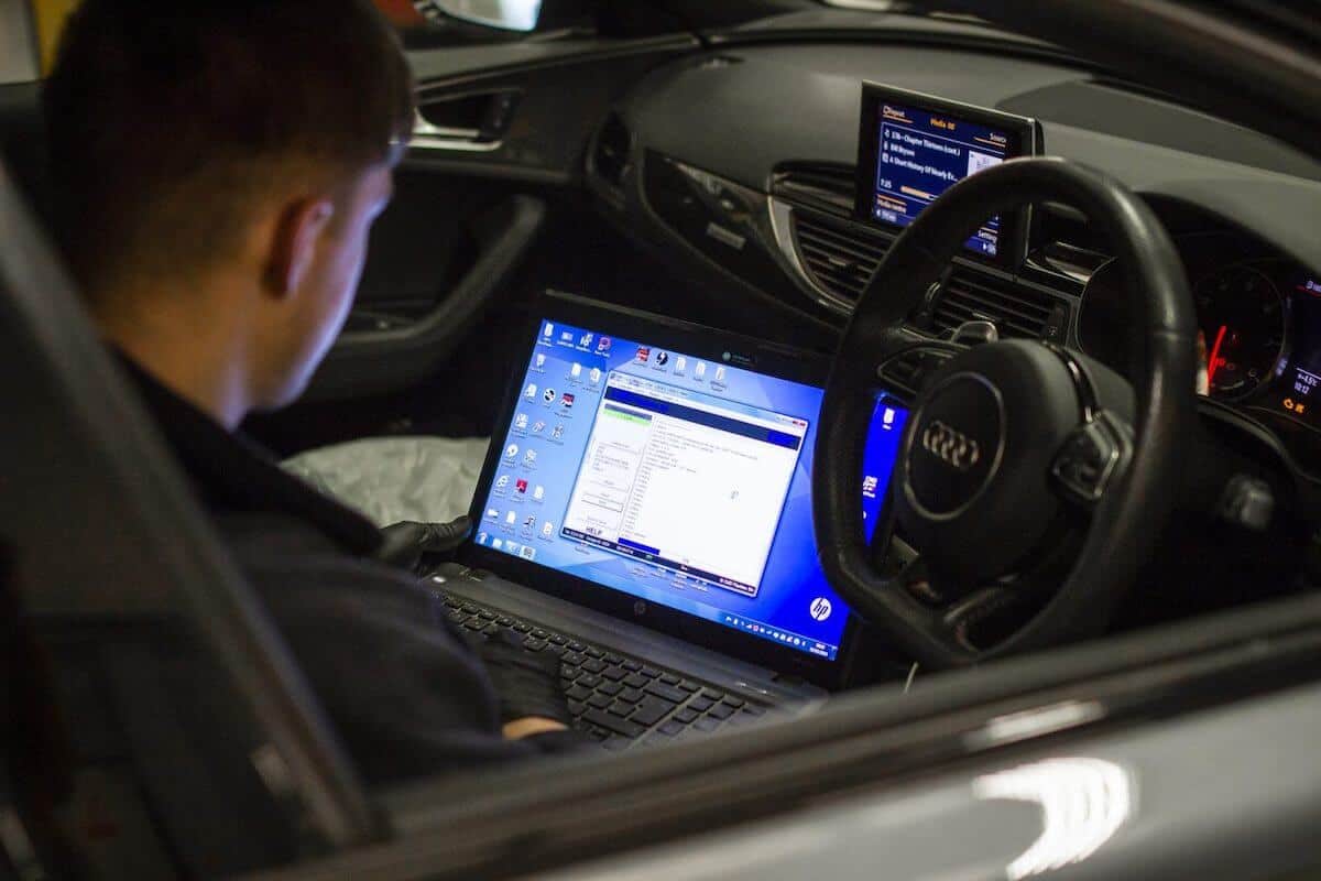 Technician using a laptop for ECU remapping inside an Audi