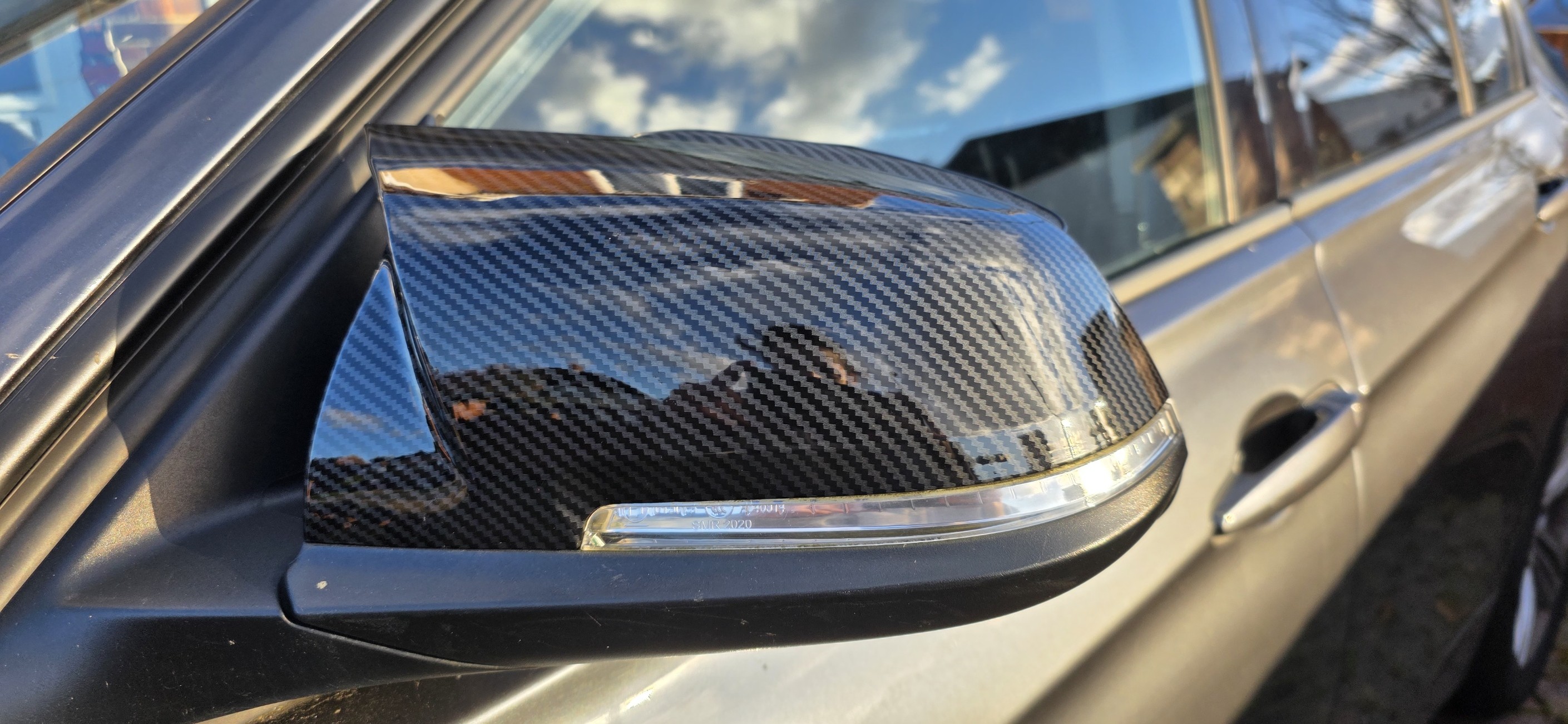 Installed carbon mirror cap close-up on a grey vehicle