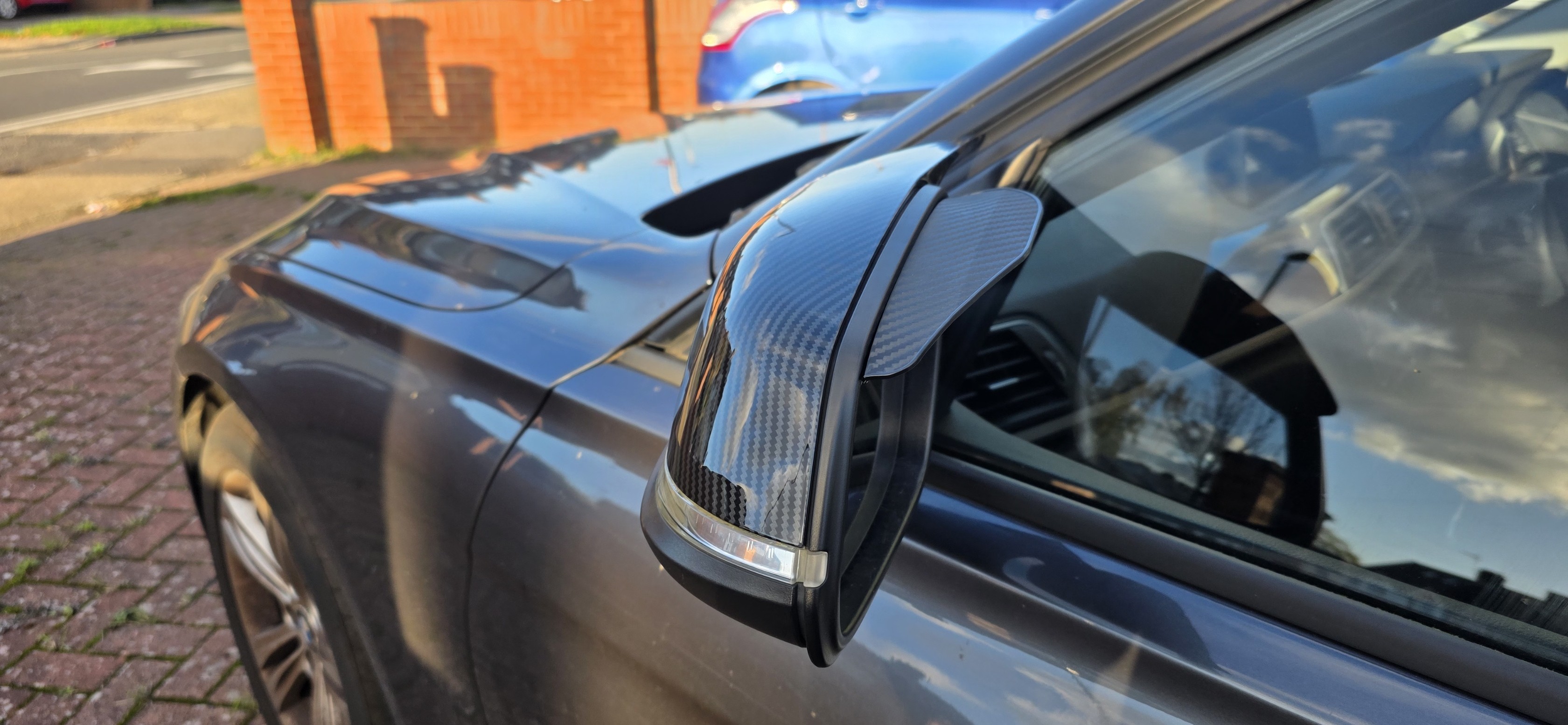 Side view of installed carbon mirror cap on a grey vehicle