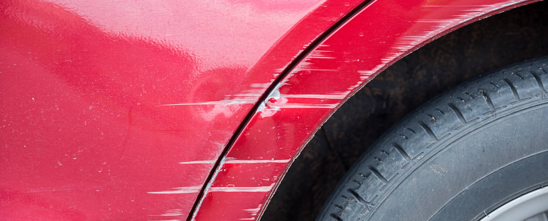 Red vehicle arch with visible scratch marks for repair assessment